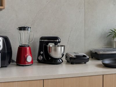 Bancada de cozinha com air fryer, liquidificador, batedeira, sanduicheira, churrasqueira elétrica e frigideira organizados.