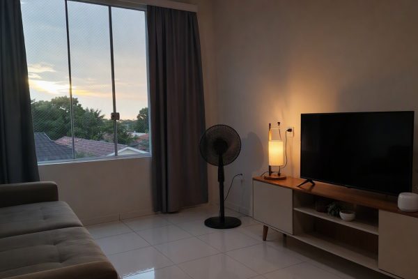 Sala com cortina blackout, tela mosquiteiro e ventilador para conforto térmico.
