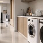 Ambiente doméstico moderno com cozinha e lavanderia integradas, ventilador de coluna e climatizador portátil ao fundo.