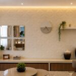 Sala de estar com parede de destaque usando adesivo texturizado, espelhos, relógio de parede, prateleira e luzes decorativas.
