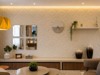 Sala de estar com parede de destaque usando adesivo texturizado, espelhos, relógio de parede, prateleira e luzes decorativas.