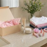 Bancada com hidratante, sérum, itens de maquiagem infantil e camisetas dobradas, sugerindo presentes de beleza para a família na Black Friday.