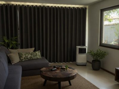 Sala na Região Norte com cortina blackout, tela mosquiteiro e climatizador portátil para conforto térmico.