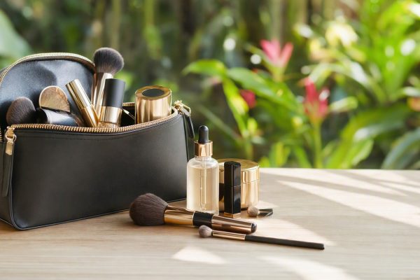 Sérum facial e itens de maquiagem organizados dentro de uma bolsa elegante, em ambiente iluminado, clima tropical ao fundo.