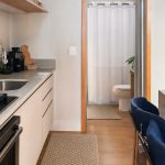 Tapetes de cozinha coordenados e cortina de box branca em ambientes integrados, com decoração neutra e organizada.