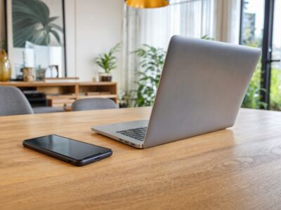 Smartphone e notebook sobre mesa de madeira em ambiente interno iluminado, representando compras online sem pessoas.