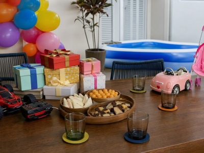 Mesa decorada para festa de Dia das Crianças em casa com brinquedos, presentes e lanches, sem pessoas.
