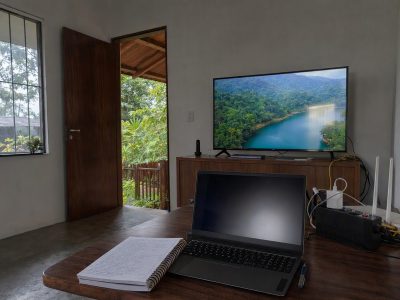 Espaço de estudo com TV exibindo aula online, mesa organizada e chuva vista pela janela, pensado para uso de Starlink na Região Norte.