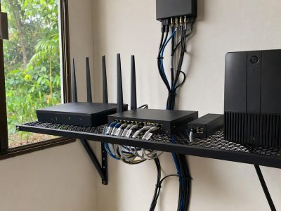 Prateleira com roteador, switch gigabit, nobreak e injetor PoE organizados para redundância com Starlink.