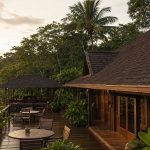 Pousada na Amazônia com antena de internet via satélite no telhado e deck externo cercado de floresta.